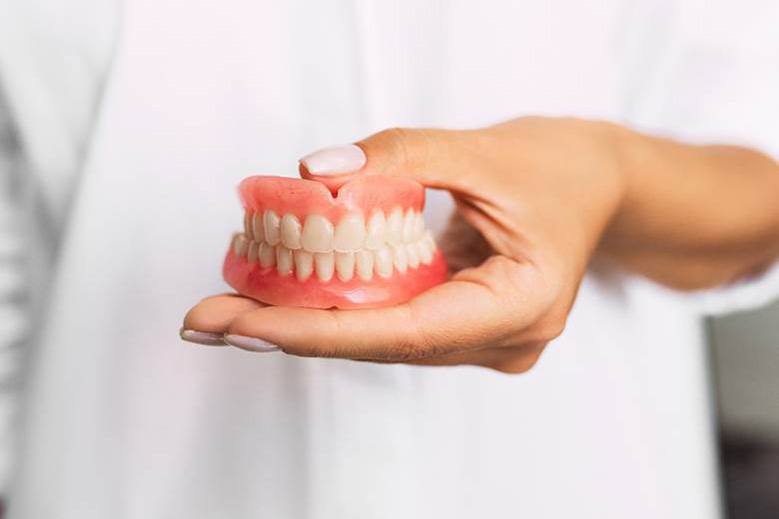 Dentist holding full dentures at Crowsnest Dental in Blairmore, Alberta